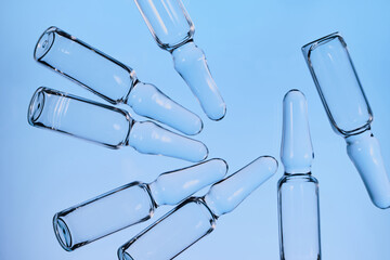 Ampoules with medicine against blue background, representing medical innovation and vaccine development © colnihko