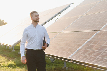 Man with tablet standing at solar panel farm © Serhii