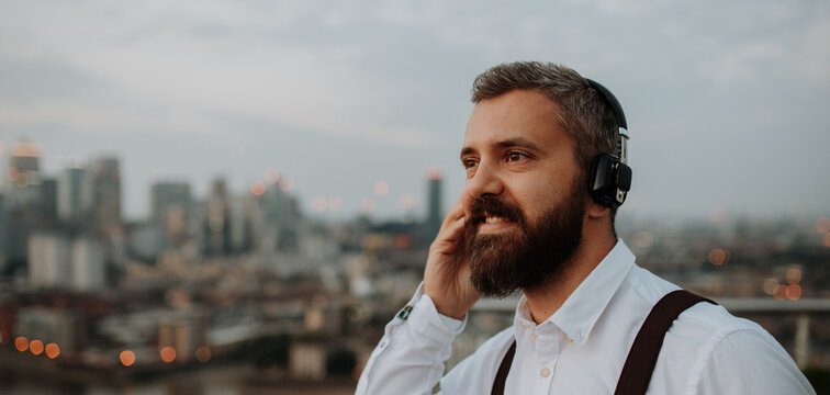 Businessman with headphones in the city, listening to music.