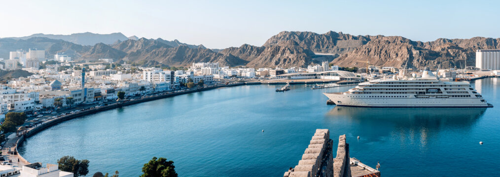 Oman, Muscat -29 November 2025. Wide panoramic scene of Mutrah Corniche capturing entire bay, curved shoreline, white architecture and the yacht of Sultan positioned along the harbor