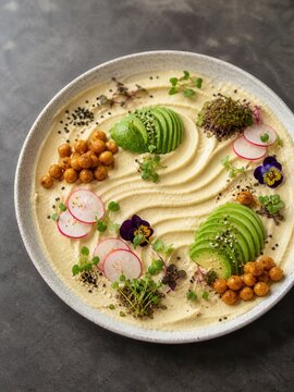 Hummus Zen Garten mit Avocado und Kichererbsen
Kreativ angerichteter Hummus mit Avocado, Radieschen, Microgreens und essbaren Bl&uuml;ten.