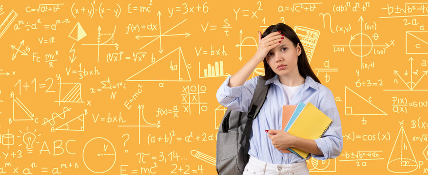 A student stands with a backpack and books. She looks worried and confused in front of a large wall filled with math formulas. It is study time in a learning environment.
