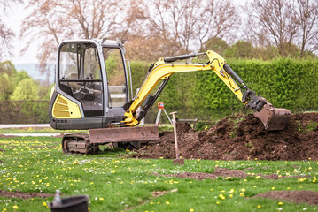 Naklejka premium Compact excavator working in garden yard landscaping and ground preparation