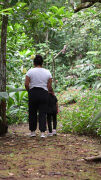 Mother and daughter holding hands walking on a forest path
