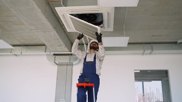 Technician repairing ceiling air conditioner ventilation system