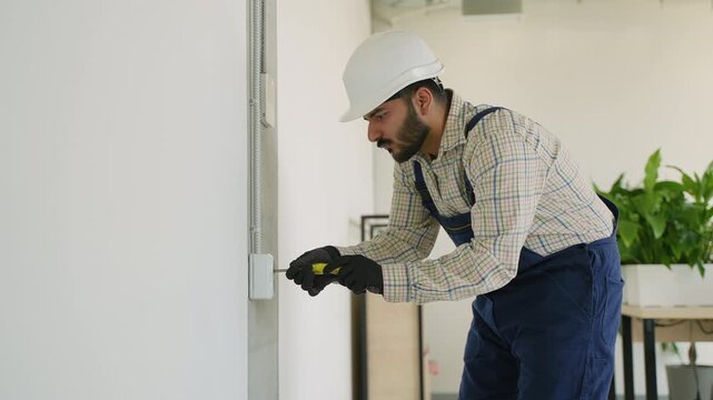 Electrician installing a wall socket using a screwdriver