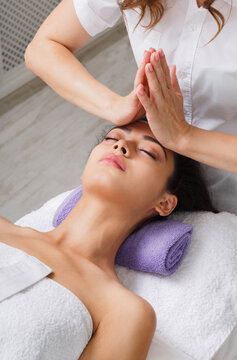 Head and face pummeling massage in spa. Beautician work in wellness center. Professional massagist make relax healthy procedure to beautiful indian woman in cosmetology cabinet or beauty parlor.