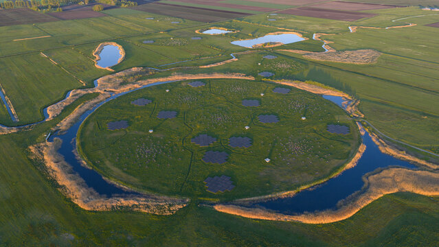 Aerial view of the LOFAR superterp radio telescope station featuring circular antenna arrays on a green island surrounded by water and lush fields Buinen, Drenthe, Netherlands.