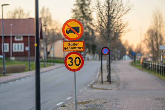 Swedish road sign indicating truck restriction and speed limit in quiet suburban street.