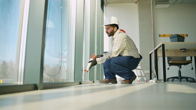 Construction worker applying silicone sealant to a window frame