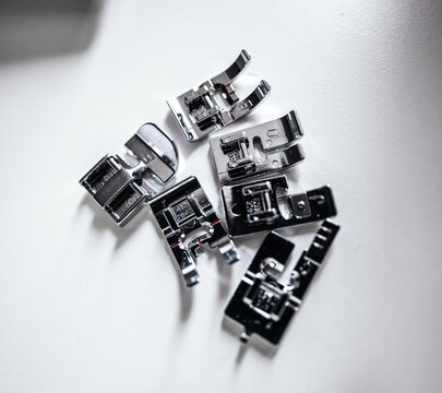 Collection of sewing machine presser feet accessories on work surface.