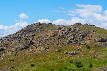 Fototapeta premium Rocky terrain on a hillside with blue sky and clouds during the daytime near a natural location