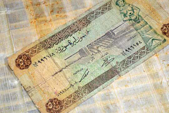 The obverse side of a collectible Syrian 50 Pounds banknote issued by the Central Bank of Syria, features the Euphrates Dam (Tabqa Dam) and a statue
