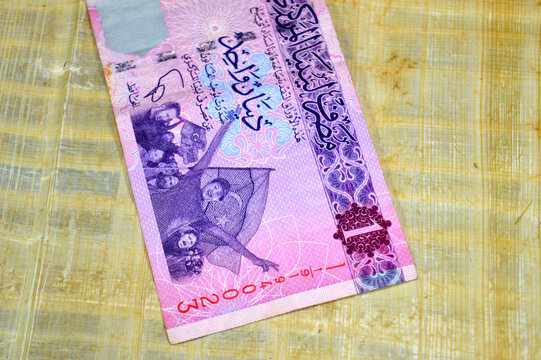 The obverse side of a 1 Libyan Dinar banknote issued by the Central Bank of Libya, featuring a scene of cheering citizens celebrating with the post-revolution Libyan flag