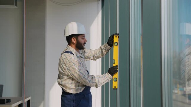 Construction worker using spirit level on window frame