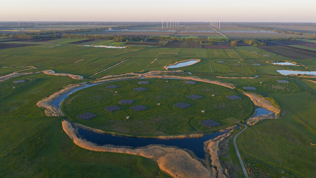 Aerial view of the LOFAR superterp radio telescope core with antenna arrays on a circular mound surrounded by water and green fields in Buinen, Drenthe, Netherlands.