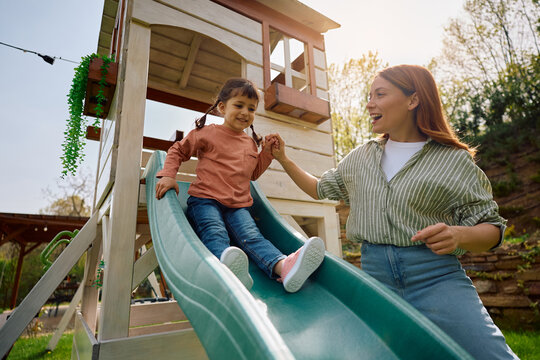 Carefree mother and daughter in enjoying day on playground.