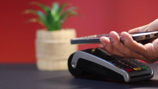 Customer using nfc contactless payment on smartphone, tapping mobile phone on pos terminal for a successful transaction and secure cashless purchase in a store