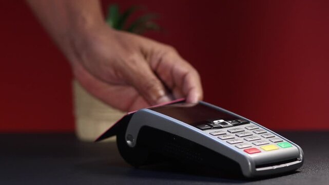 Customer swiping a credit card through a pos terminal for a purchase, making a secure electronic transaction for goods and services in a retail store or restaurant