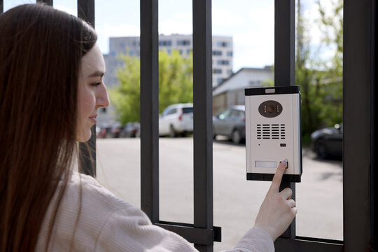 Woman pressing button on intercom panel outdoors