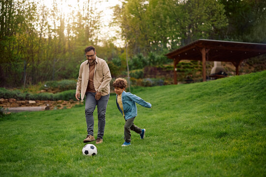 Happy boy and his father playing soccer at park.
