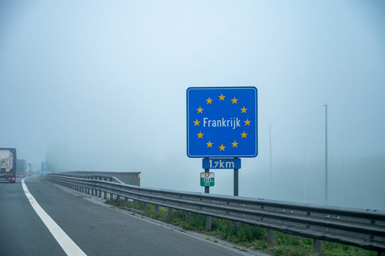 View of a French border sign on  autoroute with overhead directional signs pointing to major cities like Paris, Bordeaux, Lille, Calais, showing lanes, traffic and motorway infrastructure, road signes