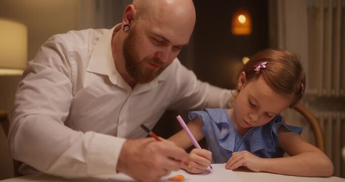 A father and daughter share joyful moments as they create colorful drawings together under soft evening lights