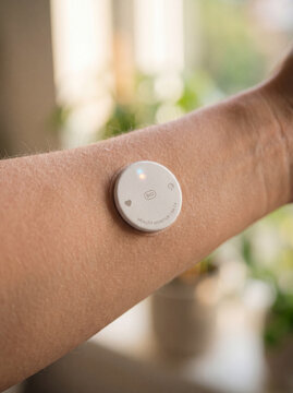 White circular health biosensor patch adhered to human skin longevity monitoring