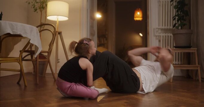 Joyful exchanges unfold as a dad and his little girl bond over fun exercises in their warm, inviting living space