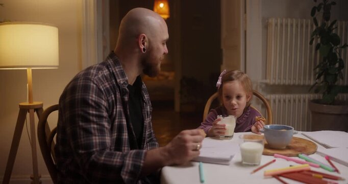 A father and daughter share artistic joy, creating colorful crafts under warm lights in their inviting space