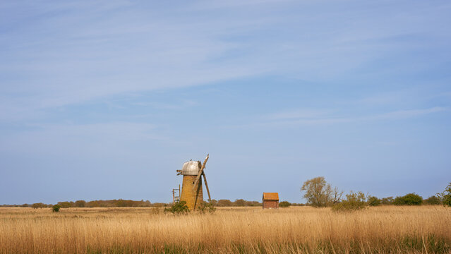 A dilapidated windmill and shed in a field on the Norfolk Broads