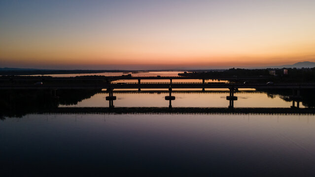 Aerial view of the Jhelum River bridge at sunset with silhouettes of vehicles and calm water reflections Jhelum, Punjab, Pakistan.