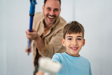 Fototapeta premium Father son painting home wall together for renovation
