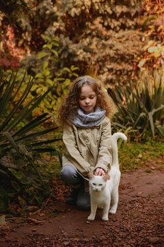 Happy little child girl with cat. Portrait of kid with pet.