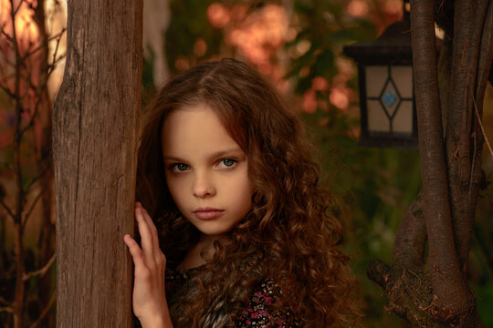 Little cute smiling girl in funny cat hat with long curly hair. Autumn seasonal portrait of young girl outdoor in the garden. Kid fall portrait. Child in the autumn garden. Selective focus, close up