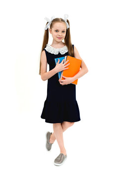 Happy cute child girl in school uniform holding books.