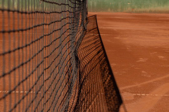 clay tennis court in europe with shadow of net 