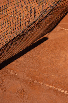 clay tennis court in europe with shadow of net 