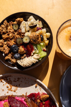 Healthy breakfast bowl at brunch restaurant with granola, blueberries, bananas, kiwi, nut butter and flaxseeds.