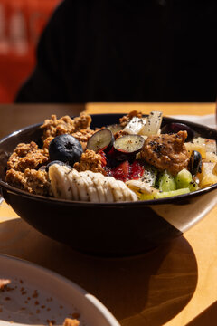 Healthy breakfast bowl at brunch restaurant with granola, blueberries, bananas, kiwi, nut butter and flaxseeds.
