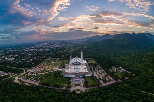 Aerial view of Faisal Masjid nestled at the foot of the Margalla Hills with its iconic white marble architecture under a vibrant sunset sky Islamabad, Islamabad Capital Ter, Pakistan.
