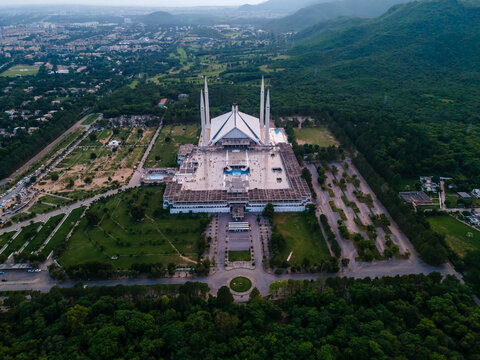 Aerial view of the iconic Faisal Masjid with its white marble structure and four tall minarets nestled against the lush green Margalla Hills Islamabad, Islamabad Capital Ter, Pakistan.