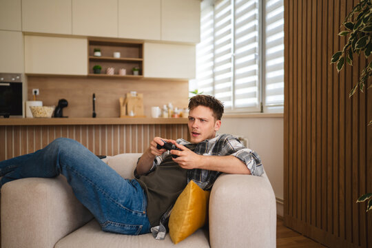 Young man relaxing on couch playing video game