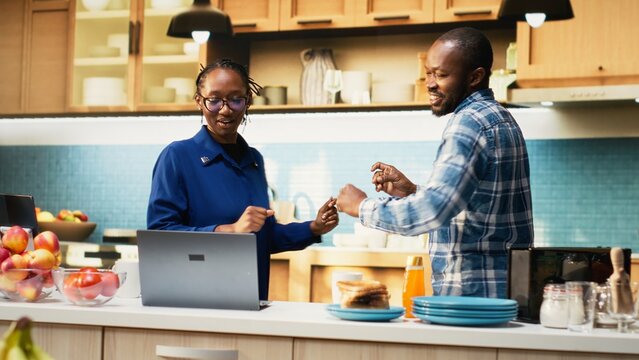 Playful smiling couple dancing in the kitchen and enjoying morning music. Groovy and goofy moves showing romantic passion, happiness and the beauty of a loving relationship at home.