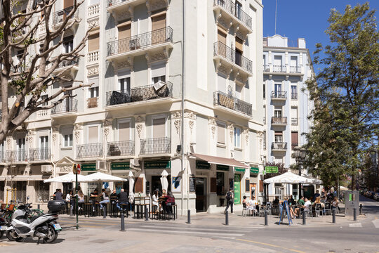 wide angle city corner scene in Russafa, Valencia, with apartments and cafes on a sunny day