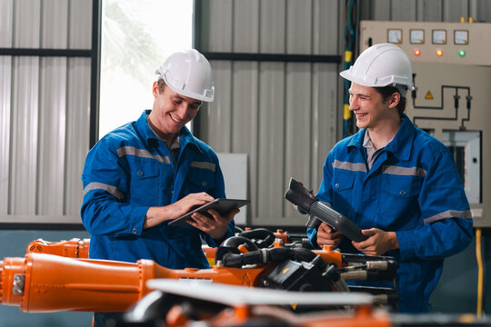 Industrial robot arm auto production factory worker safety helmet blue uniform quality control digital tablet teamwork maintenance check engineering Industrial robot arm auto production factory