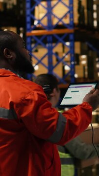 Vertical Video Scanning awb details, information on tablet, black man using scanner, in industrial fulfillment center. Staff member emphasizing manual labor for order fulfillment and e-commerce