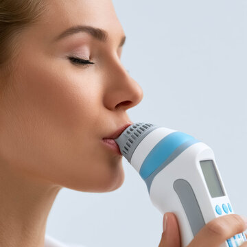 Woman using spirometer device for lung function test, respiratory therapy, breathing exercise and medical diagnostics concept