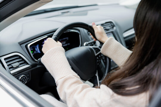 A young girl sits inside a car holding the steering wheel.