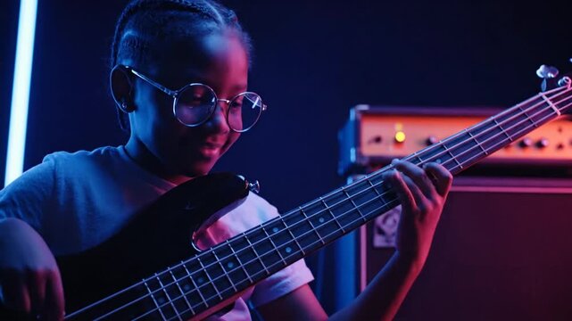 Young Child Playing Electric Bass Guitar in a Colorful Music Studio with Dynamic Lighting and Amplifier
